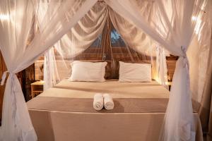 a bed with two white towels sitting on it at Vila do Junco in Santo Amaro