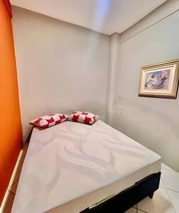 een kleine kamer met een bed met rode en witte kussens bij Cantinho Perfeito Em Matinhos in Matinhos