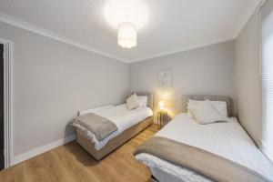 two beds in a room with white walls and wooden floors at 12 osbourne road in Gillingham