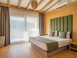 a bedroom with a large bed and a large window at Perast Garden Hotel in Cıralı
