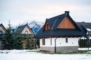 a house with a black roof with mountains in the background at Domek u Jurgowiana in Jurgów