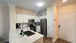 a kitchen with white cabinets and a black refrigerator at Relaxing Pool-View 1BR Near Top Houston Spots in Houston