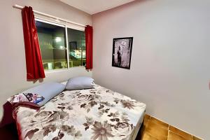 een slaapkamer met een bed en een raam met rode gordijnen bij Quarto Praia Economico in Matinhos