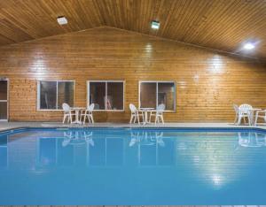 a swimming pool with chairs and a wooden wall at Baymont by Wyndham Baldwin in Baldwin