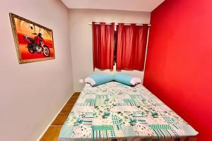 una piccola camera con un letto con una parete rossa di The Red, Vem que tem Sol a Matinhos