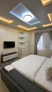 een slaapkamer met een groot wit bed en een televisie bij Imperial luxe homes in Araromi