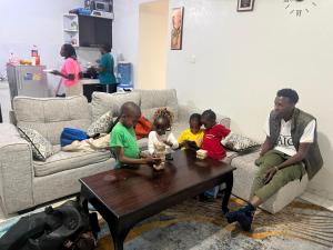 een man die op een bank zit met een groep kinderen bij kire homes in Nakuru +2 foto's