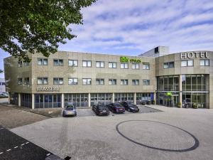 een groot gebouw met auto's ervoor geparkeerd bij ibis Styles Almere in Almere