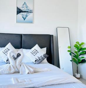 een bed met witte lakens en kussens erop bij The Sunset Bangsaen in Ban Rong Khoei