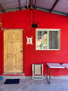 een rode muur met een houten deur en een bankje bij Cabañas Mountain View in Paso Ancho