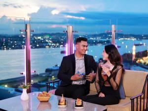 a man and a woman sitting on a couch with drinks at Mercure Samarinda in Samarinda