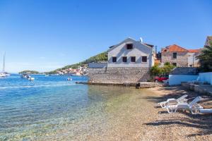 een strand met stoelen en een huis en het water bij Apartments Mat in Vis