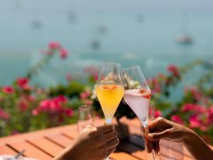 Zwei Personen halten Getränkegläser auf einem Tisch hoch. in der Unterkunft V Villas Phuket - MGallery Collection in Panwa Beach