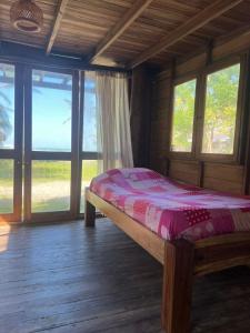 een slaapkamer met een bed in een kamer met ramen bij CARPE DIEM oceanfront cabin private beach in San Bernardo del Viento