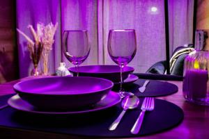 een tafel met paarse borden en wijnglazen erop bij Le lodge étoilé in Égat