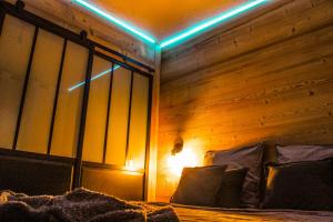 een slaapkamer met een houten muur en een bed met kussens bij Le lodge étoilé in Égat