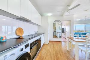 een keuken met witte kasten en een tafel en een eetkamer bij Cullen Bay Resorts in Darwin