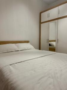 een slaapkamer met een wit bed en een spiegel bij Apartment DUNJA Laktasi in Laktaši