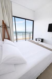 een witte slaapkamer met uitzicht op de oceaan bij Maraga Bento in Maragogi