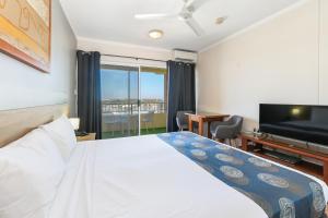een slaapkamer met een bed en een flatscreen-tv bij Cullen Bay Resorts in Darwin