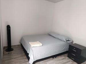 a bedroom with a bed with a nightstand and a white wall at NaGLo1527 in Estación El Salto