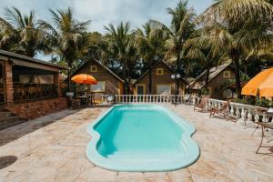 a swimming pool in a yard with a house at Pousada Chalés Jardim das Aguas in Olímpia