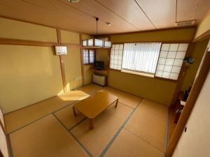 una stanza vuota con un tavolo e due finestre di ペンション歩野慕野-honobono a Kitashiobara