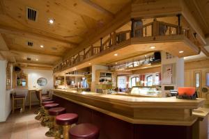 a bar in a restaurant with wooden ceilings and stools at Hotel Alpenpanorama in Söll