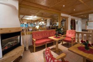 a living room with red chairs and a fireplace at Hotel Alpenpanorama in Söll