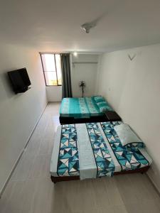 two beds in a small room with a window at Apartamento Completo Perfecto in Cartago