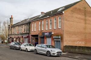 Drei Autos parkten vor einem Backsteingebäude in der Unterkunft Cosy Retreat Suites in Hamilton