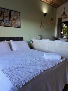 een wit bed in een kamer met een wastafel bij Chalé vista da vila in Sao Jorge