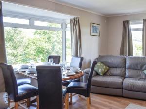 a dining room with a table and a couch at Lilybank Cottage in Doularg