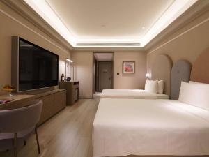 a hotel room with two beds and a flat screen tv at Mercure Xi'an Stadium Hotel in Xi'an