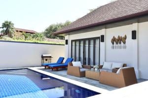 eine Villa mit Swimmingpool und einer Terrasse mit blauen Stühlen in der Unterkunft Rawai - Luxury 2 bedroom Private Pool Villa in Ban Saiyuan (1)