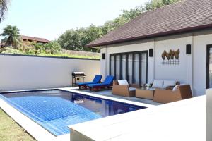 einen Hinterhof mit Pool und Stühlen und ein Haus in der Unterkunft Rawai - Luxury 2 bedroom Private Pool Villa in Ban Saiyuan (1)