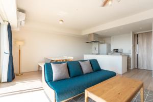een woonkamer met een blauwe bank en een tafel bij KAI Okinawa in Kitanakagusuku