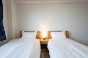 twee bedden in een kamer met een lamp op een bureau bij KAI Okinawa in Kitanakagusuku