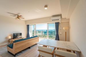 een woonkamer met een bank en een eettafel bij KAI Okinawa in Kitanakagusuku