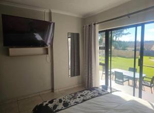 una camera da letto con un letto e una TV a schermo piatto di Peite Grounds Inn a Polokwane