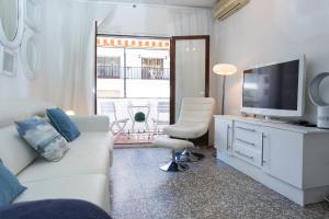 sala de estar con sofá blanco y TV en Du Soleil Apart, en Sitges