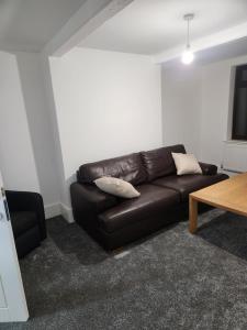 un salon avec un canapé en cuir marron et une table dans l'établissement Redlane, à Warmingham
