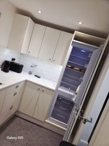 La cuisine est équipée de placards blancs et d'un réfrigérateur ouvert. dans l'établissement Redlane, à Warmingham