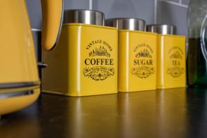 Eine Reihe von vier gelben Behältern stand auf einem Tisch in der Unterkunft Central Location! 15 mins to Airport 2 mins to High Street and Station FREE PARKING!! in Birmingham