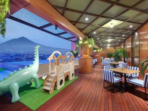 ein Restaurant mit einem Pool und einem Dinosaurier auf dem Deck in der Unterkunft Mercure Garut City Center in Garut