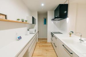 a kitchen with white counters and a sink at 藤乃宿 ペットと暮らすように泊まる宿 in Sapporo