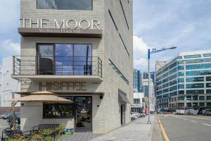 a building with a sign that reads the moore watches from the street at The Moor in Busan