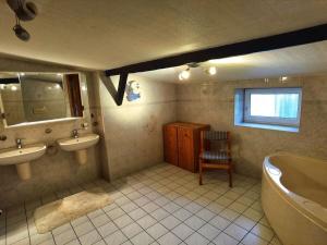 een badkamer met 2 wastafels, een bad en een spiegel bij Farmhouse for arrival in Lütjenwestedt