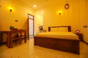 a bedroom with a bed and a table and a chair at Happy Corner Ahangama in Midigama West