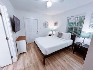 a white bedroom with a bed and a window at Beach Getaway One Block from the Beach in Pompano Beach